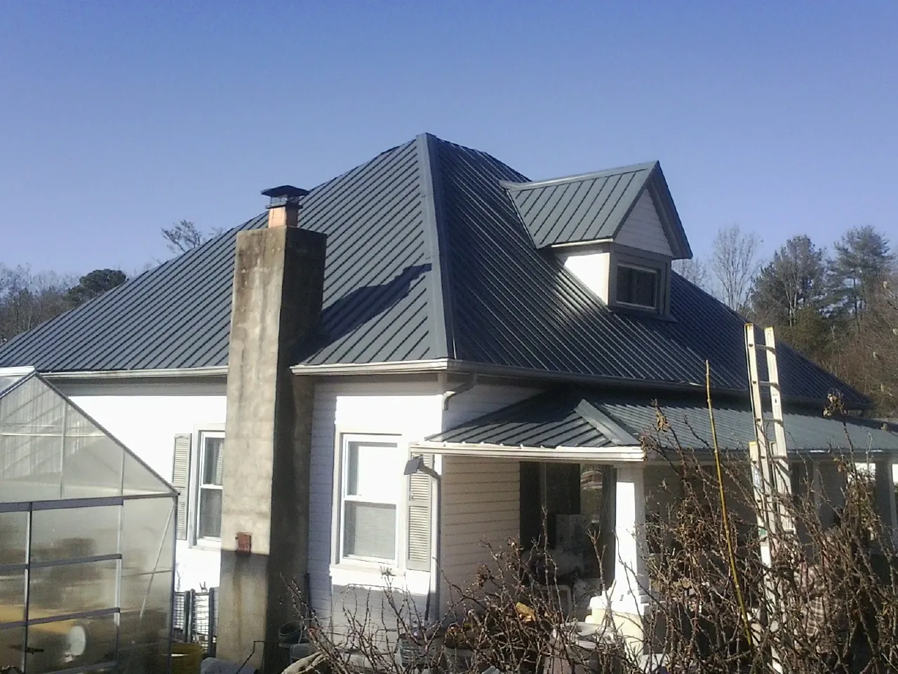Dark blue standing seam metal roof on a white farmhouse with dormer — Slate & Tile Roof Repair by Roofing Brothers in Carrolltown