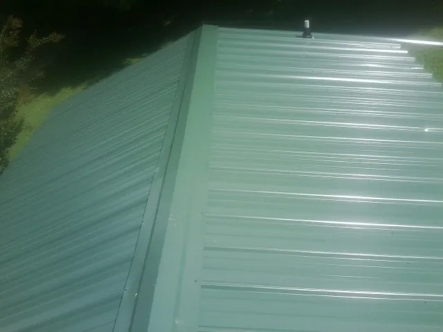 New green metal panels meeting at the ridge of a roof — Flat Roof Repair work by our crew in Carrolltown