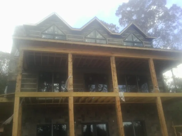 Dormers and porch framing on a large log home under construction — Roof Coating work by our crew in Carrolltown