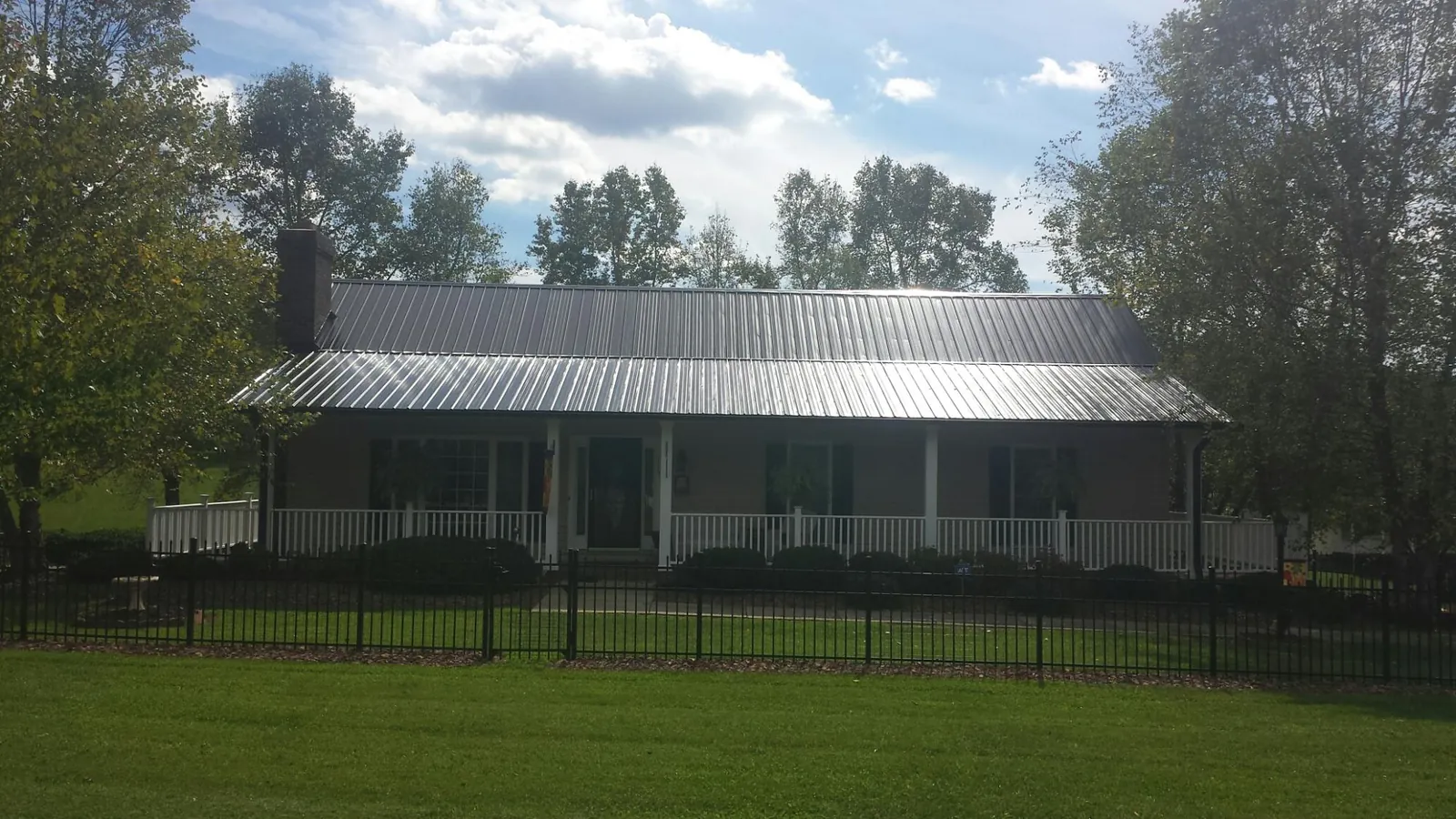 Gray metal roof on a brick ranch with a full width front porch — Gutter Guard Installation work by our crew in Carrolltown