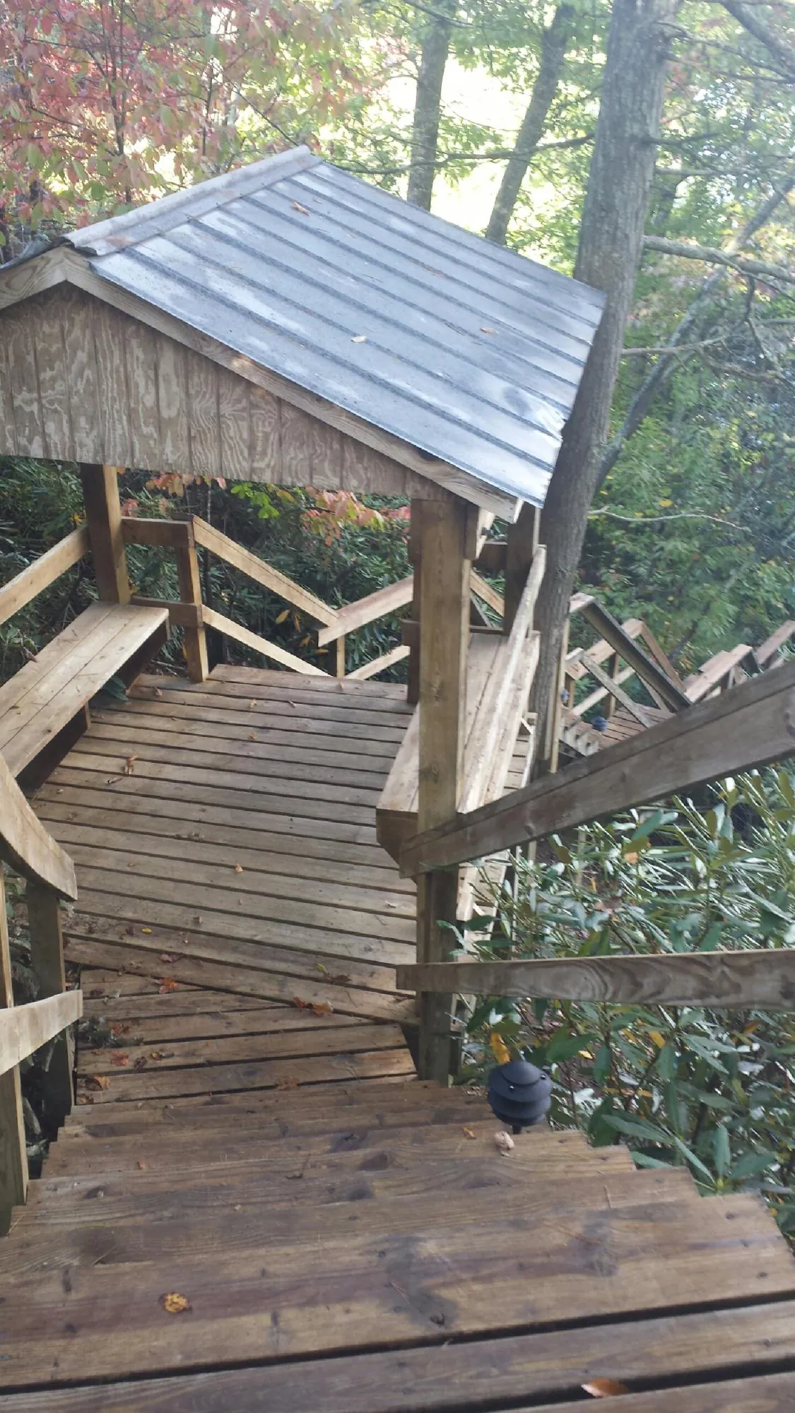 Metal roofed shelter over wooden steps on a wooded walkway — Skylight Repair & Installation work by our crew in Carrolltown