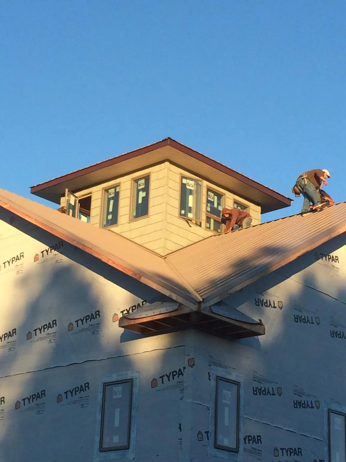 Roofers working around a rooftop cupola on a new metal roof at sunset — Roof Waterproofing in Carrolltown by Roofing Brothers